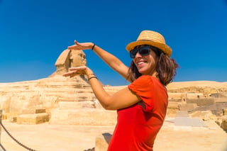 A tourist in a red dress, pyramids behind, Egypt