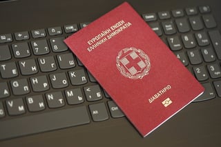 Greece passport lies on the laptop keyboard