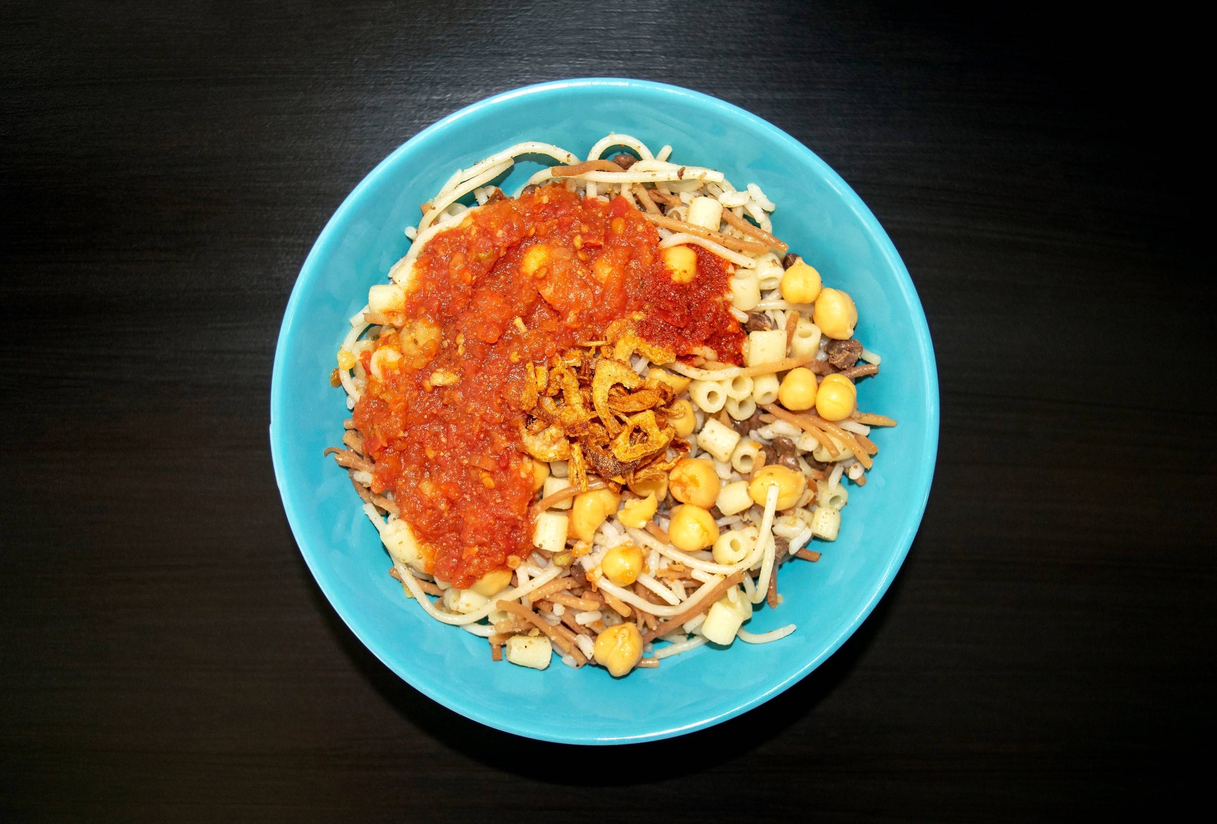 Koshari, plato egipcio con salsa de tomate.