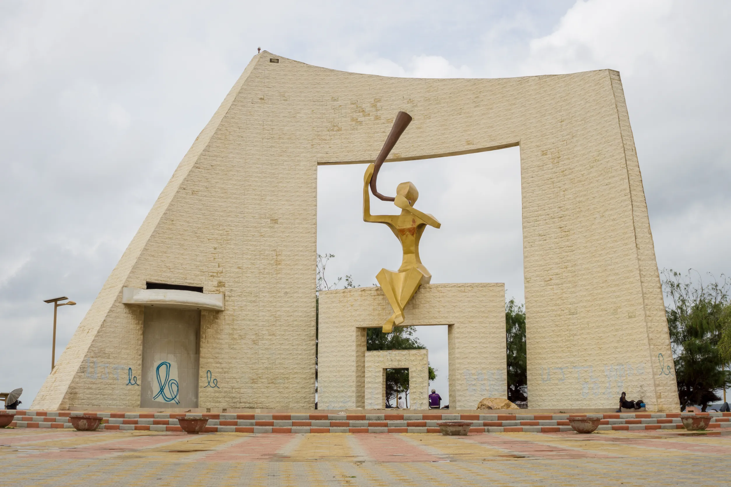 statue of a woman blowing a horn in a public area of the city of dakar